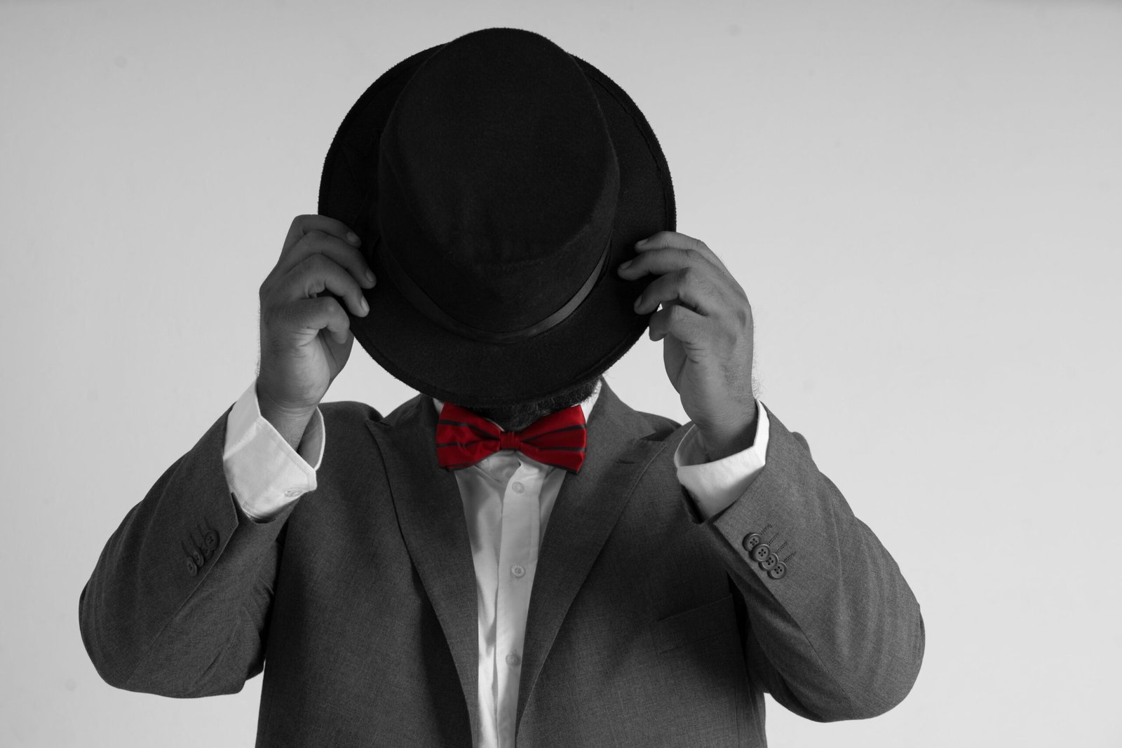 Foto a blanco y negro siendo el modelo nuestro mago profesional Eduardo Aviña posando con un sombrero en su rostro de manera sutil