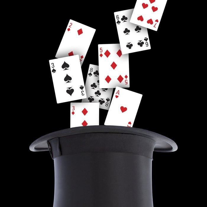 Sombrero de mago de color negro del cual salen cartas de la baraja inglesa simulando apariciendo con el fondo negro